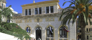 Historic Municipio of Kerkira, Greece, featuring elegant architecture and palm trees, set against a clear blue sky.