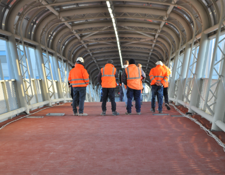 Construction workers in safety gear walking on a newly constructed walkway, emphasizing industrial services and teamwork in a professional environment.