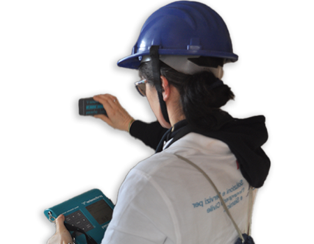 A person in a blue hard hat using a handheld device to monitor controls, demonstrating safety and technology in a work environment.
