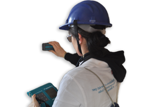 A person in a blue hard hat using a handheld device to monitor controls, demonstrating safety and technology in a work environment.